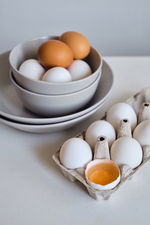 Chicken eggs on minimalist plates. Art photo with uncooked eggs on white table. Natural organic farm product. Preparing for Easter holiday. Kitchen art, dish on cuisineの写真素材