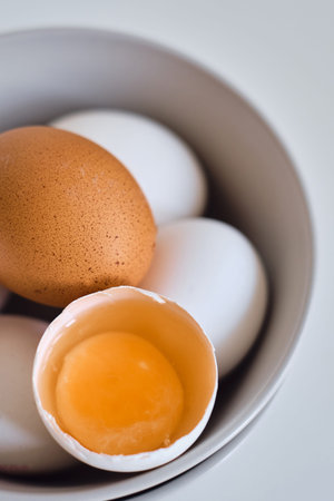 Chicken eggs on minimalist plates. Art photo with uncooked eggs on white table. Natural organic farm...