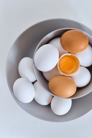 Chicken eggs on minimalist plates. Art photo with uncooked eggs on white table. Natural organic farm product. Preparing for Easter holiday. Kitchen art, dish on cuisineの写真素材