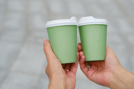 Green paper cup with coffee in woman hand. Time for drink coffee in city. Coffee to go. Enjoy...