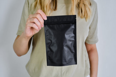 Kraft black paper packaging in a woman hands. Packaging for coffee, cosmetics. Packing closeup....