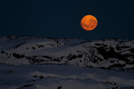 huge moon in the night sky over one of the Antarctic islands