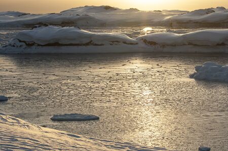Strait between the islands covered by ice of Antarctica at sunsetの写真素材