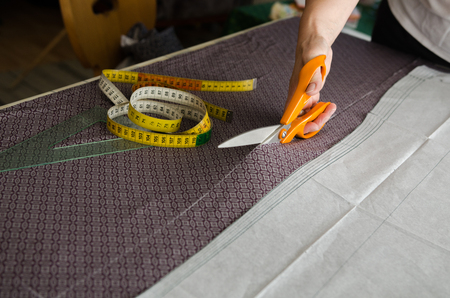 Woman hand cuts a piece of fabric before sewingの写真素材