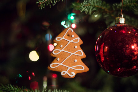 Gingerbread hanging on the christmas tree with light garland and glass spheresの写真素材