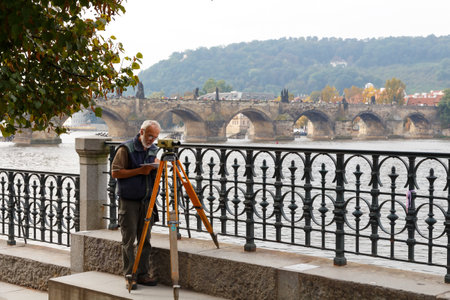 Prague, Czech Republic - September 30, 2014: The man in front of Charles Bridge carries topographic binding theodolite.のeditorial素材