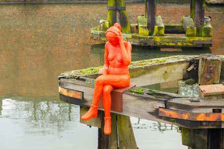Ghent, Belgium - December 31, 2014: Famous sculpture red naked girl in headphones on the river Leie.のeditorial素材