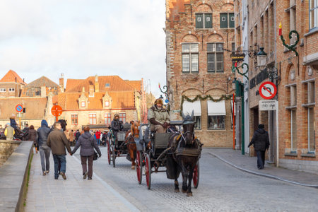 Bruges, Belgium - December 25, 2014: Horse-drawn carriage on the ancient streets of Bruges. Popular activities among tourists.のeditorial素材