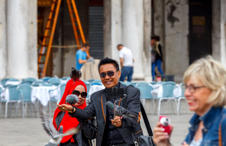 Venice Italy May 20 2015: Tourists are photographed on St. Mark39s Square with pigeons. Pigeons fly in the area for the food from the tourists.のeditorial素材