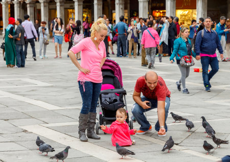 Venice Italy May 20 2015: Tourists are photographed on St. Mark39s Square with pigeons. Pigeons fly in the area for the food from the tourists.のeditorial素材