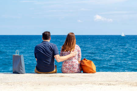 Man and  woman on the beach in an embrace looking at the sea.の写真素材