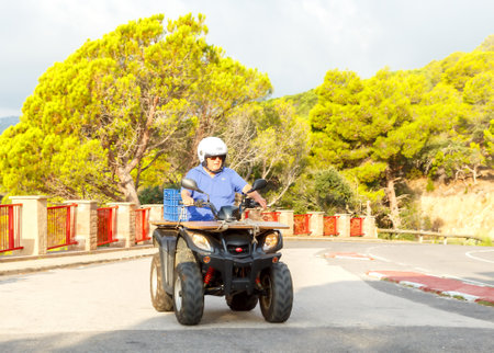 Tossa de Mar, Spain - September 12, 2015: Man controls the ATV on a mountain road. Quad bike is a means of of the raised passableness.のeditorial素材