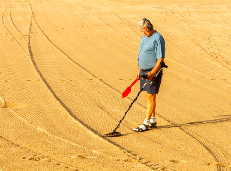 Tossa de Mar, Spain - September 12, 2015: Man looking for lost jewelry with metal detector on the beach of Tossa de Mar. Famous tourist resort on the Mediterranean coast.のeditorial素材