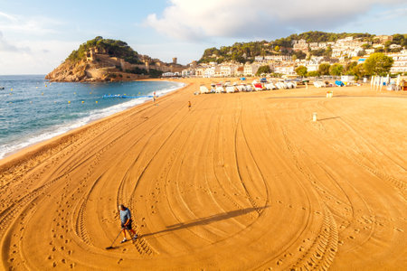 Tossa de Mar, Spain - September 12, 2015: Man looking for lost jewelry with metal detector on the beach of Tossa de Mar. Famous tourist resort on the Mediterranean coast.のeditorial素材