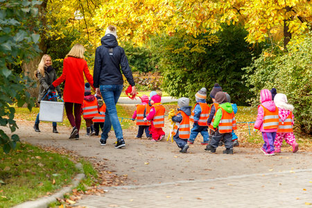 Tallinn, Estonia - October 19, 2015: A kindergarten teacher with small children dressed in reflective safety vests for a walk in the park in Tallinn.のeditorial素材