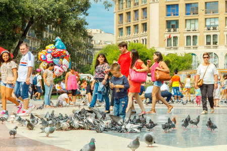 Barcelona, Spain - September 6, 2015: Tourists feed the pigeons in Plaza Catalunya in Barcelona. Plaza de Catalunya is one of the main attractions of the Spanish capital.のeditorial素材