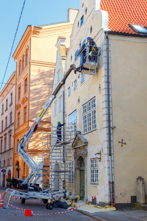 Riga, Latvia - 15 October, 2015: Working with the lifting device being restored facade of the old building. The historic center of Riga attracts many tourists.のeditorial素材