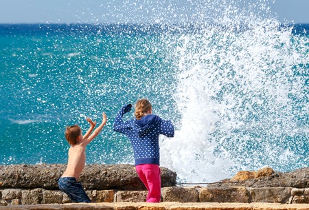 Boy and girl running away from the waves on the waterfront of Chania.の写真素材