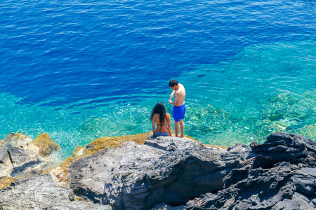 Santorini, Greece - April 28, 2016: The rocky beach near the village of Oia on Santorini. The harbor is visited by large number of tourists.のeditorial素材