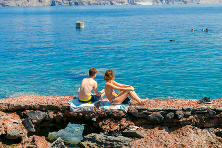 Santorini, Greece - April 28, 2016: The rocky beach near the village of Oia on Santorini. The harbor is visited by large number of tourists.のeditorial素材