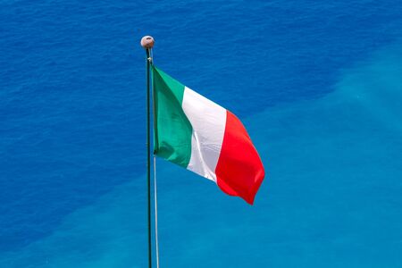 The Italian national flag on a background of blue sea in the village Vernazza.の写真素材