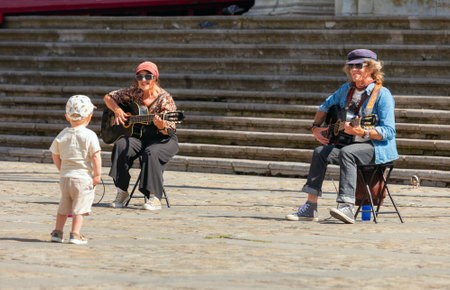 Street musicians guitarists give a concert for kid tourist in the city square.のeditorial素材
