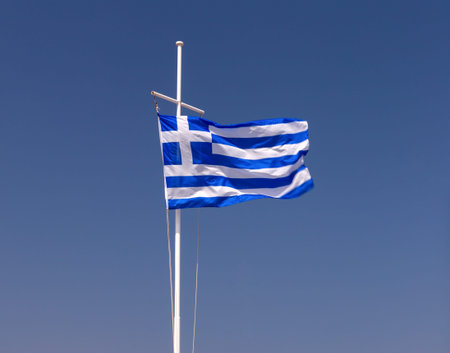 Greek national flag fluttering against a blue sky.