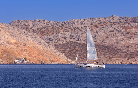 White yacht against the backdrop of high mountains in the bay of Symi island.の写真素材