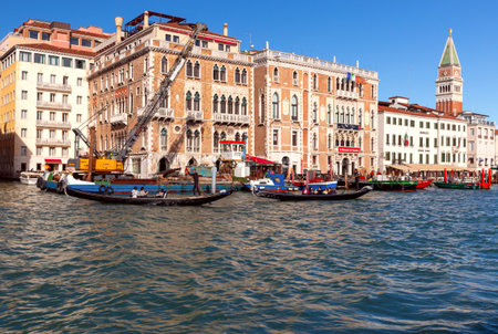Gondoliers with tourists in a gondola float along the canal on a sunny day.のeditorial素材