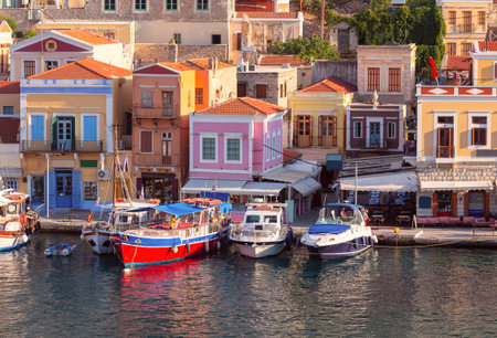 Multi-colored facades of houses in the village of Symi at sunset.
