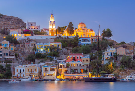 Multi-colored facades of houses in the light of lanterns in the village of Symi at sunset.の写真素材