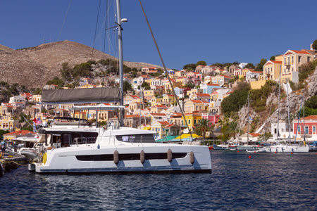 Bright multi-colored facades of houses on the shore of the bay in the village Symi