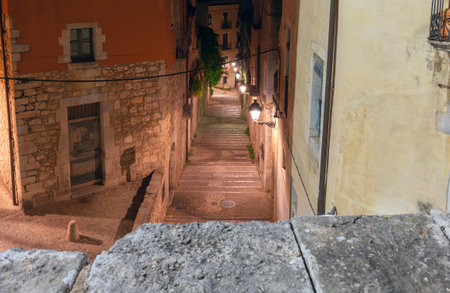 Old historic street illuminated at night in Girona, Spainの写真素材