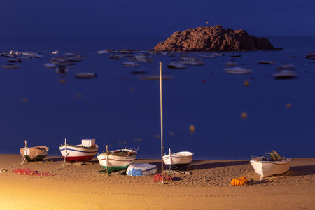 Fishing boats on the beach at night in Tossa de Mar, Spainの写真素材