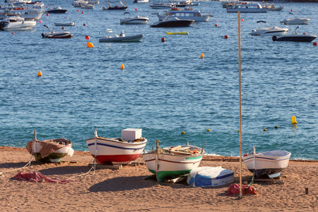 Fishing boats on the sandy beach of Tossa de Mar at sunrise, Spainの写真素材