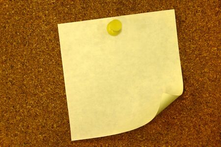 Yellow curled blank memo on bulletin board with copy spaceの写真素材