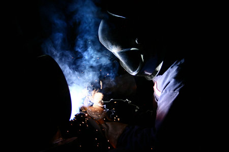 A welder arc-welds steel piping in a factory.の写真素材