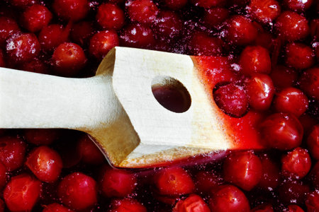 Wooden spoon for stirring when cooking cherry jamの写真素材