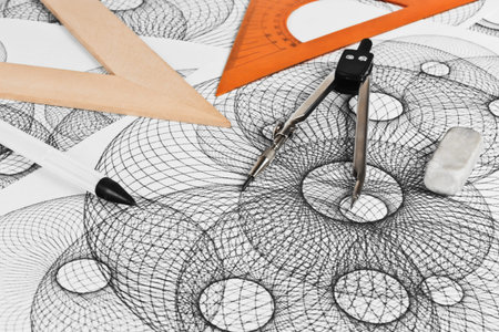Circinus, ruler, pencil and eraser on a background sheet of paper with abstract geometric shapes
