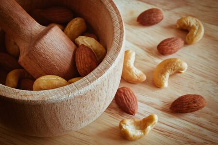 A mixture of various nuts in a wooden mortar and pestle made of hard wood on a cutting boardの写真素材