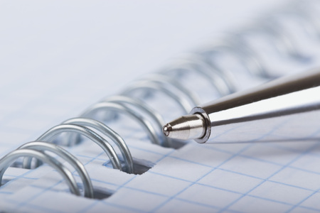 Metal ballpoint pen close-up on the opened notebookの写真素材