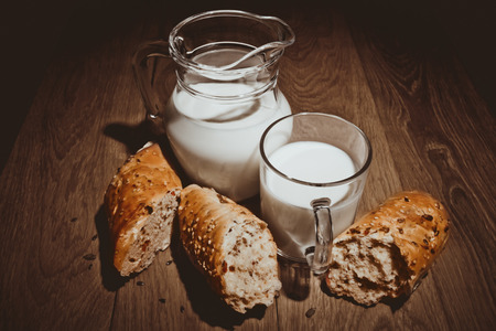 Milk and buns with cinnamon on the oak tableの写真素材