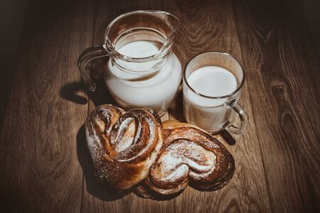 Milk and buns with cinnamon on the oak tableの写真素材