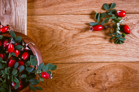 Rosehip fruits, twigs and green leaves on a wooden backgroundの写真素材