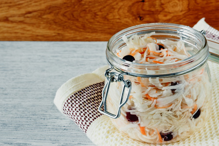 Sour cabbage with cranberries in a glass jar on a wooden backgroundの写真素材