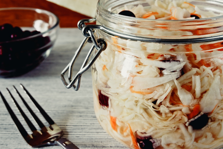 Sour cabbage with cranberries in a glass jar on a wooden backgroundの写真素材