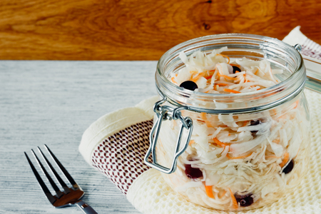 Sour cabbage with cranberries in a glass jar on a wooden backgroundの写真素材