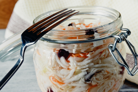 Sour cabbage with cranberries in a glass jar on a wooden backgroundの写真素材