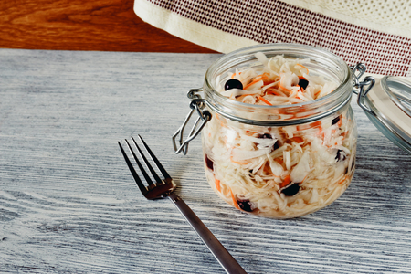 Sour cabbage with cranberries in a glass jar on a wooden backgroundの写真素材