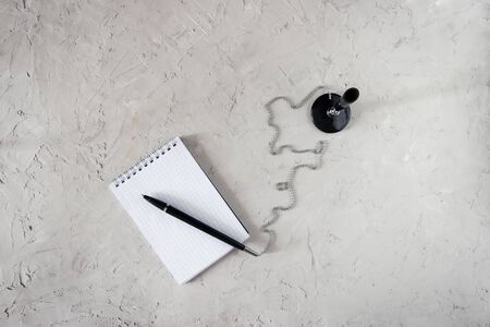 Writing pen on a chain and an open notebook on a gray concrete backgroundの写真素材